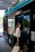 Person steigt mit Stofftasche in einen modernen Linienbus an einer Haltestelle ein.
