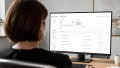 Eine Frau, die über die Schulter fotografiert wurde und auf einen Desktop-Screen schaut, auf dem das Dashboard von Testamanagement® zu sehen ist.