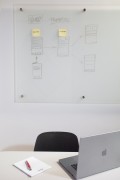 Unbesetzter Schreibtisch mit einem Laptop und einem Notizblock vor einem Whiteboard.