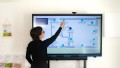 A woman stands at a large touch display and selects a point on the floor plan.