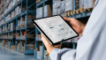 A person holds a tablet in his hands showing the KION Design System called “Parcel” in an application. The person is in a warehouse.