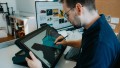 A UXMA employee is sitting at a digital drawing board, working on the final design of the power tool.