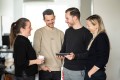 Four UXMA employees stand around a tablet laughing and looking at the content on it.