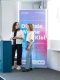 Two female UXMA employees stand behind a podium on a stage at the Digital Week Kiel.