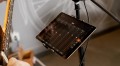 Image of a tablet with a music mixer interface. Next to it, a guitar.