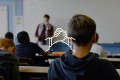 An icon of a handshake on the background of a classroom bench with young people facing the blackboard.