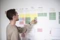 Person steht vor Whiteboard mit Post-its.
