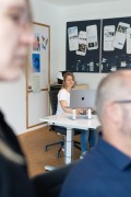 Designerin arbeitet am Schreibtisch. Hinter ihr hängen Home Connect Plakate.