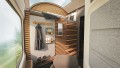 A Nigthexpress cabin with a bunk bed above which there is a panoramic window. On the side of the bunk bed there is a wardrobe and compartments for shoes, magazines, etc. In front of it there is an armchair.