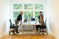 UXMA employees talk and laugh across a desk.
